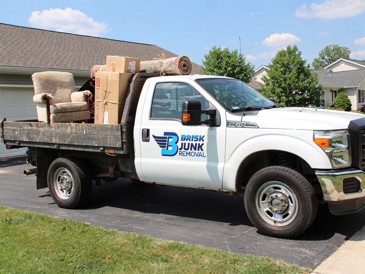 White Ford F-250 loaded with household junk in a suburban driveway