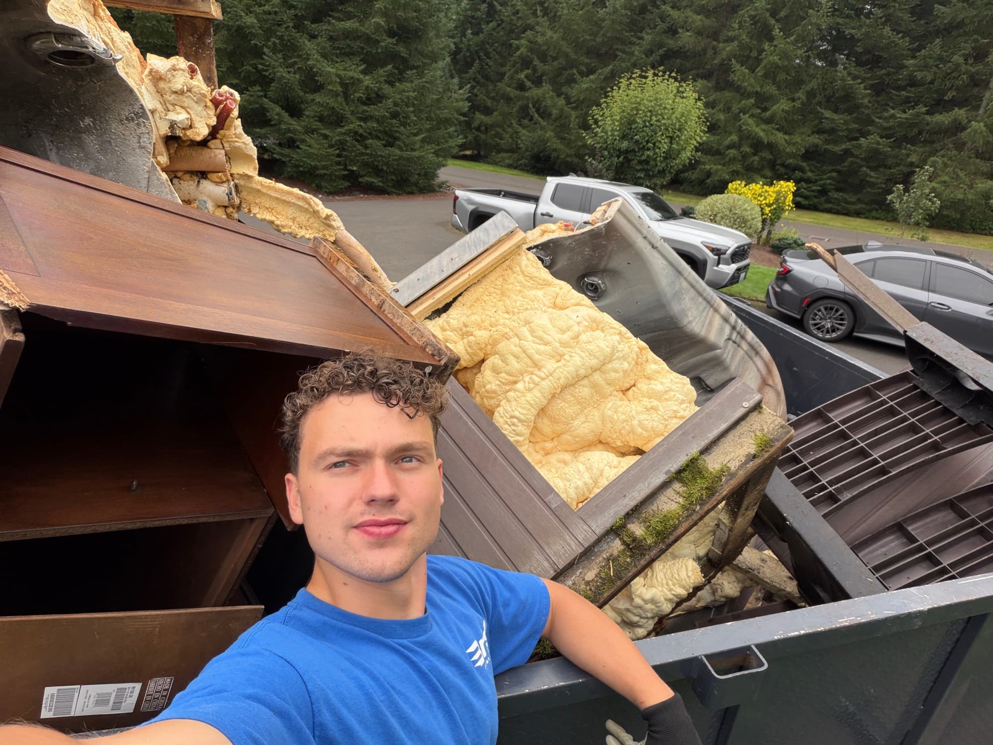 Brisk Junk Removal crew member with a trailer loaded full of hauled-away junk at a local property